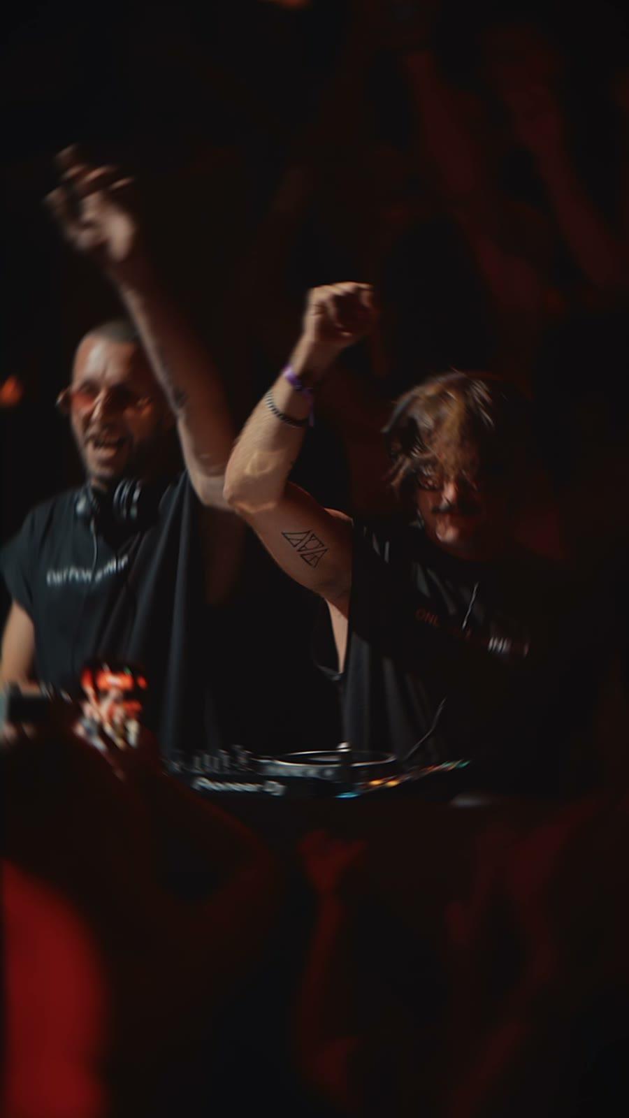 Dos DJs con los brazos en alto en Fuego